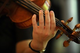 Close-up of a violinist, showing left arm, hand, and top half of the violin